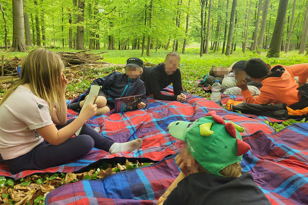 Bild zeigt Kinder auf einer Decke im Wald.