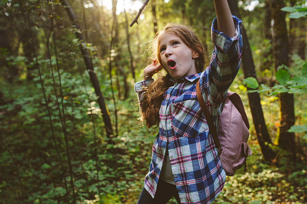 Bild zeigt ein fröhliches Mädchen im Wald.